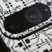 Macro shot of an electronic circuit design around a smartphone camera lens, showing intricate details.