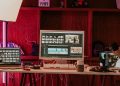 A professional video editing workspace featuring monitors, keyboard, and microphones in a studio setting.