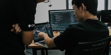 two men working on computers in an office