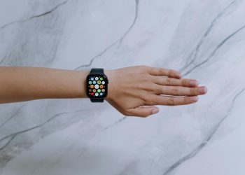 Overhead view of a smartwatch on an arm against a marble background representing modern technology.