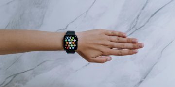 Overhead view of a smartwatch on an arm against a marble background representing modern technology.