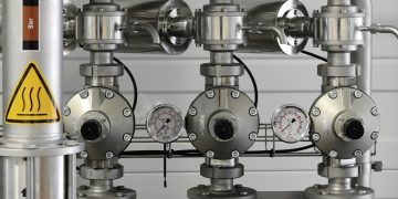 Close-up of stainless steel pipes with pressure gauges in an industrial setting.