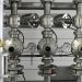 Close-up of stainless steel pipes with pressure gauges in an industrial setting.