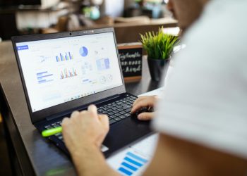 Focused business analysis with charts and graphs on a laptop in a modern office setting.