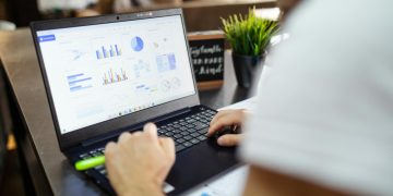 Focused business analysis with charts and graphs on a laptop in a modern office setting.