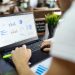 Focused business analysis with charts and graphs on a laptop in a modern office setting.