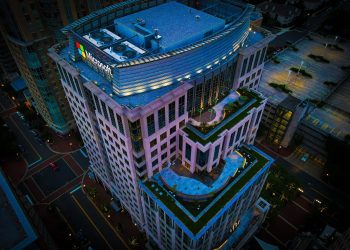 High-angle nighttime view of a modern urban skyscraper with rooftop garden.