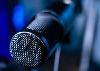 Detailed close-up of a professional studio microphone with a blurred blue background.