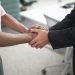 Close-up of a formal handshake between two businessmen in an office environment.