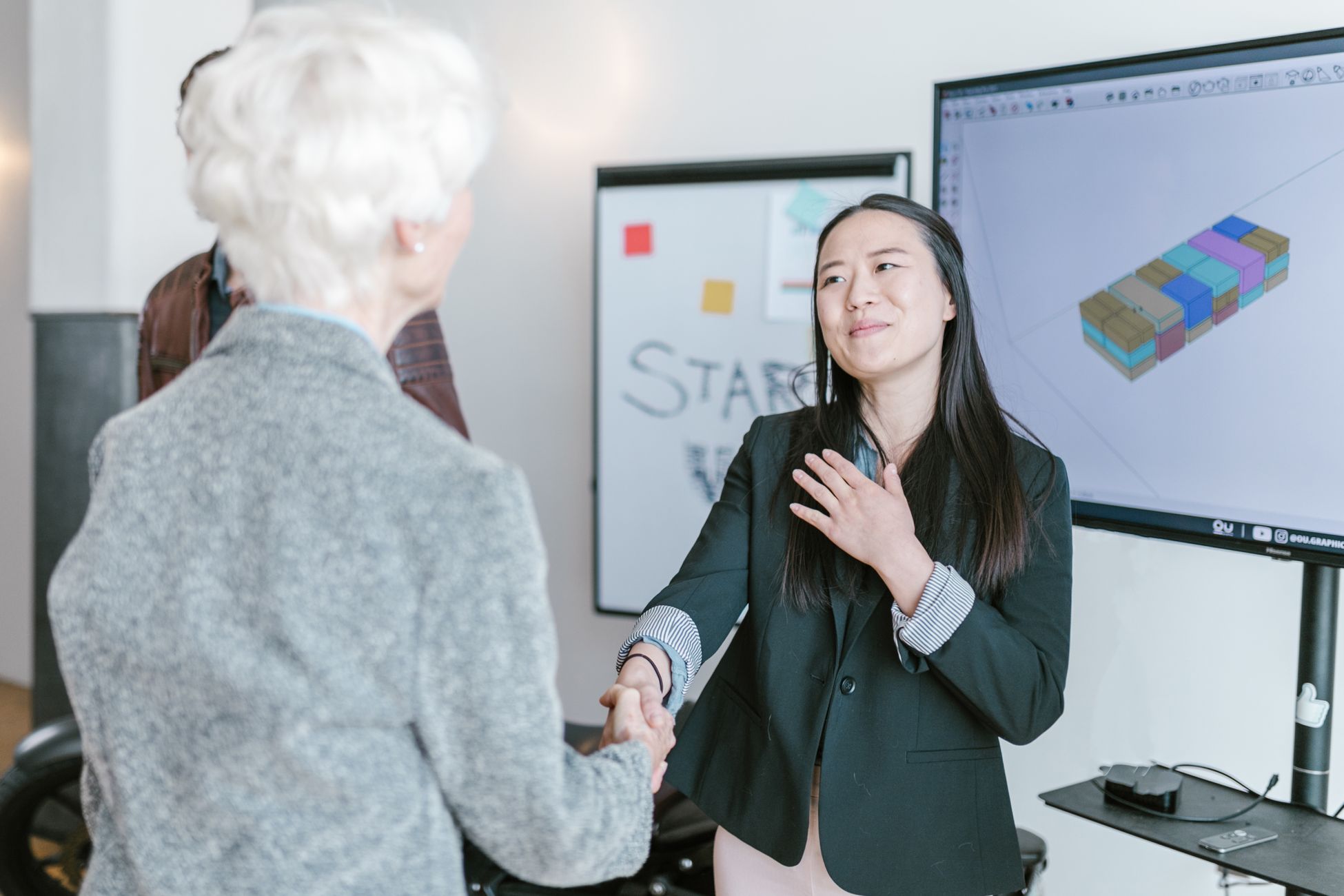 Professional women shaking hands in a corporate office setting, symbolizing a successful business agreement.