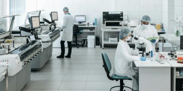 Researchers in lab coats performing experiments with advanced equipment in a laboratory.