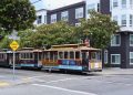 Classic San Francisco cable car on Powell and Mason, city streets, greenery, and iconic signs.