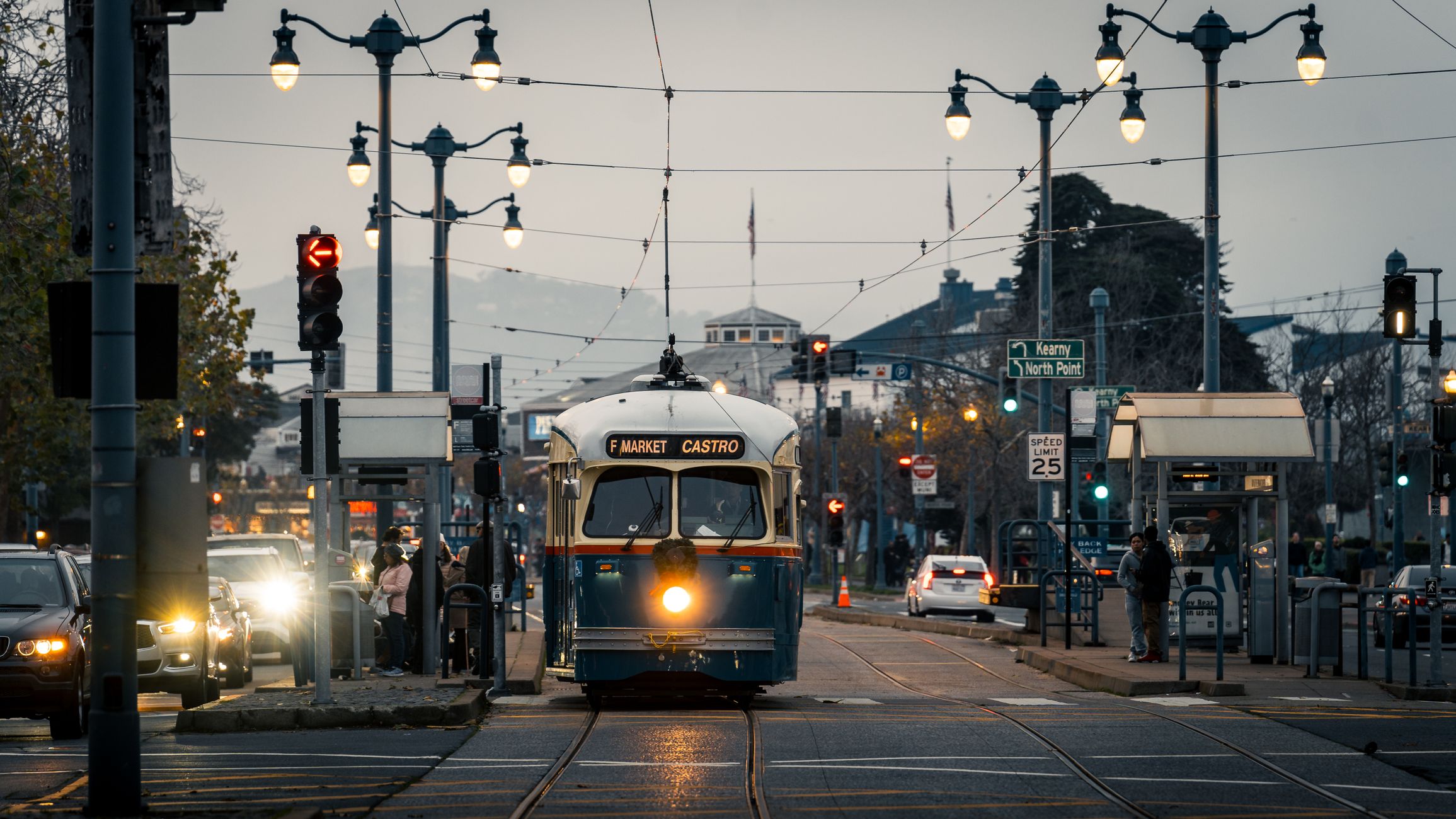 A classic streetcar on San Francisco's F Market & Castro line during dusk on a bustling city street.