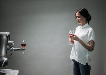 A robot presents a glass of wine to a woman, showcasing modern technology and interaction.