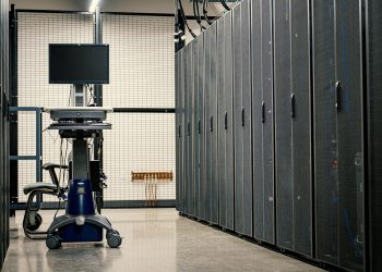 Contemporary computer on support between telecommunication racks and cabinets in modern data center