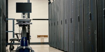 Contemporary computer on support between telecommunication racks and cabinets in modern data center