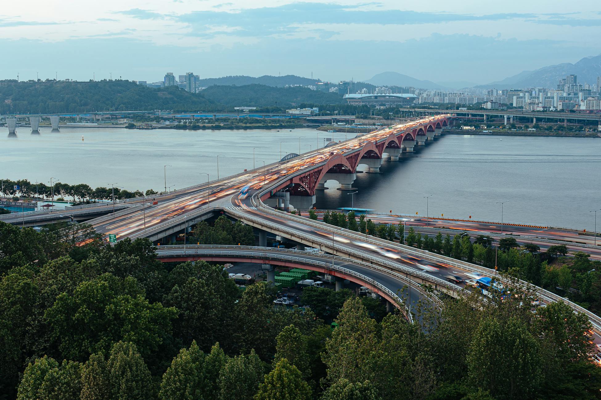 Vibrant cityscape of Seoul featuring the Han River and a dynamic bridge overpass captured at twilight.