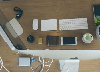 Top-down view of an organized modern desk setup featuring Apple devices and accessories.