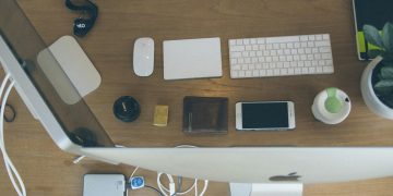 Top-down view of an organized modern desk setup featuring Apple devices and accessories.
