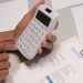 Close-up of hands using a calculator next to a company invoice, depicting a financial calculation concept.