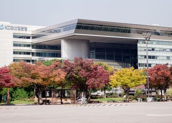 A modern urban building surrounded by colorful autumn trees in a cityscape setting.