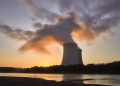 Dramatic image of a nuclear power plant at sunrise with steam rising into a colorful sky.