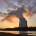 Dramatic image of a nuclear power plant at sunrise with steam rising into a colorful sky.