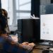IT professional working on a computer in a modern office setting, focused on coding and tasks.