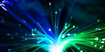 Close-up of illuminated fiber optic lights in blue and green colors, showcasing modern technology.