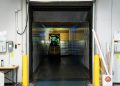 A forklift unloading goods at an industrial loading dock inside a warehouse.