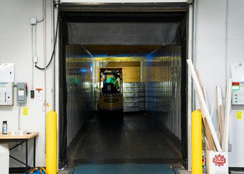 A forklift unloading goods at an industrial loading dock inside a warehouse.