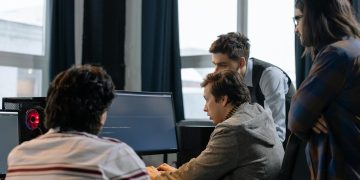Group of developers working together on a computer programming project indoors.