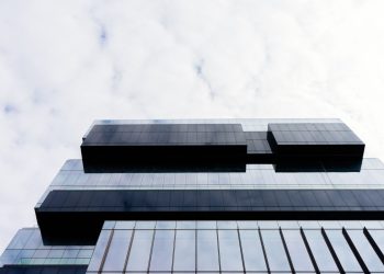 Contemporary building with a glass facade and geometric patterns, low angle view.