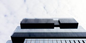 Contemporary building with a glass facade and geometric patterns, low angle view.