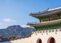View of Gyeongbokgung Palace with traditional Korean architecture set against a mountain backdrop on a sunny day.