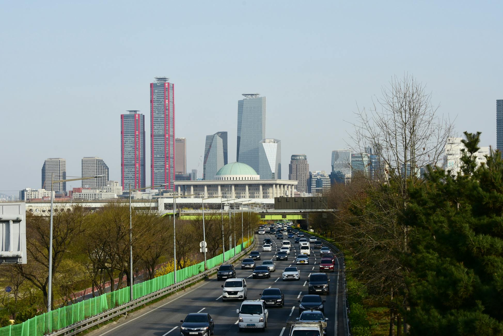 View of Seoul's skyline featuring skyscrapers and a busy highway under a clear sky.