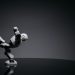 Minimalist photo of a toy robot balancing creatively in a studio setting.