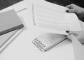 Black and white image of a businesswoman reviewing a business summary on paper.