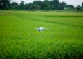 A drone hovering above a vibrant green agricultural field, showcasing modern farming technology.