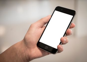 A hand holding a modern smartphone with a blank screen, ideal for design mockups.