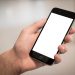 A hand holding a modern smartphone with a blank screen, ideal for design mockups.