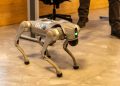 A robotic dog stands indoors, showcasing advanced technology with a sleek design.