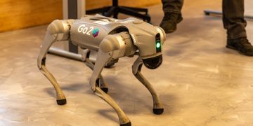 A robotic dog stands indoors, showcasing advanced technology with a sleek design.