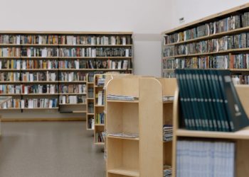 Spacious university library featuring wooden bookshelves filled with diverse books for education and research.