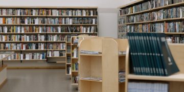 Spacious university library featuring wooden bookshelves filled with diverse books for education and research.