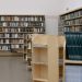 Spacious university library featuring wooden bookshelves filled with diverse books for education and research.