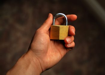 Hand holding a brass padlock, symbolizing security and protection