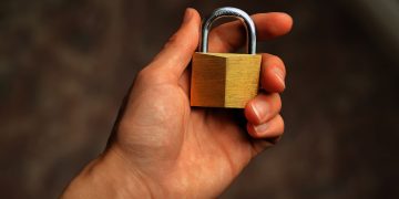 Hand holding a brass padlock, symbolizing security and protection