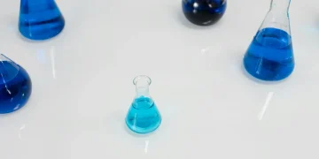 Various glass flasks filled with blue liquid in a scientific setting, perfect for research themes.
