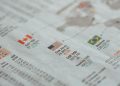 Detailed close-up of a newspaper displaying global financial market statistics and country flags.